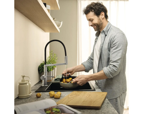 Mann wäscht Kartoffeln in einer modernen Küche mit Spültischarmatur.