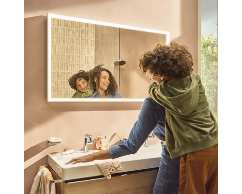 Modernes Badezimmer mit Waschbecken, beleuchtetem Spiegelschrank und Familie