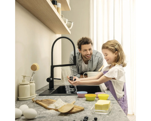 Scène de cuisine avec un père et sa fille lavant des baies à l''évier, avec un robinet moderne et des ingrédients pour la pâtisserie sur le plan de travail.