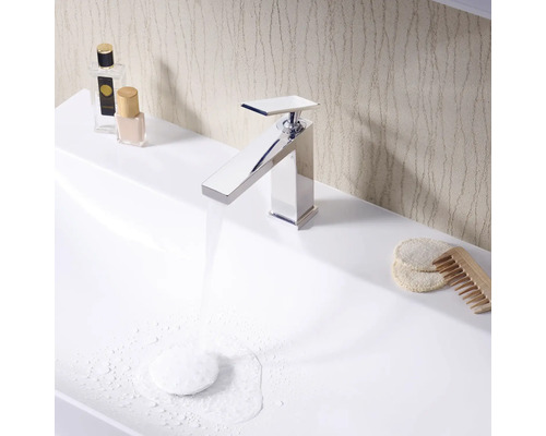 Lavabo de salle de bains moderne avec robinet chromé, produits cosmétiques et accessoires