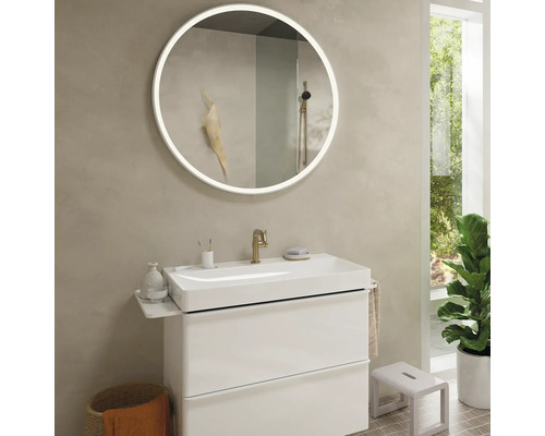 Helles Badezimmer mit rundem Spiegel, Waschbeckenunterschrank und Zimmerpflanze