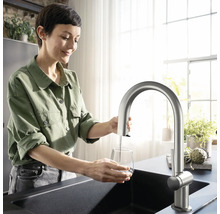 Femme remplissant un verre d''eau sous un robinet de cuisine