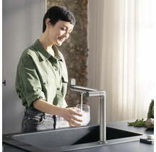 Femme remplit un verre avec un robinet sur un évier