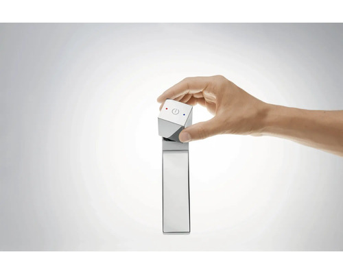 Une main actionne un robinet avec un panneau de commande cubique.