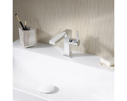 Auf einem Waschbecken befinden sich ein chromfarbener Wasserhahn, Pinsel und Seife.