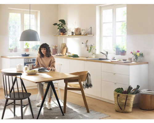 Cuisine claire avec table à manger, chaises et une femme lisant un livre