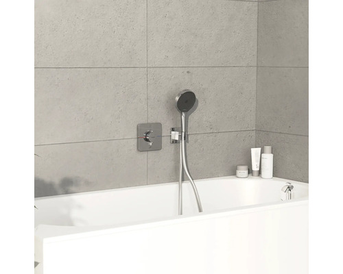 Badezimmer mit Badewanne, Duschkopf und Armaturen an einer gefliesten Wand