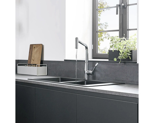 Küchenspüle mit Wasserhahn und Küchenutensilien vor Fenster