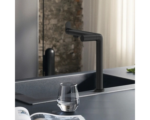 Robinet noir sur un évier avec un verre d''eau.