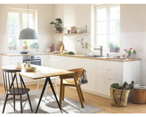 Helle Küche mit Esstisch, Stühlen und Küchenutensilien.