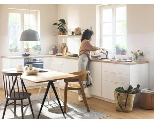 Cuisine claire avec kitchenette, table à manger et une personne à l''évier