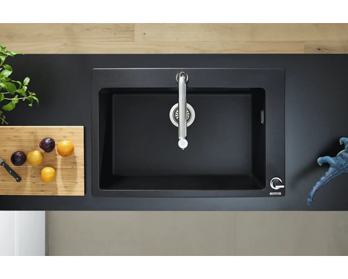 Évier noir avec robinet sur un comptoir de cuisine avec planche à découper et prunes