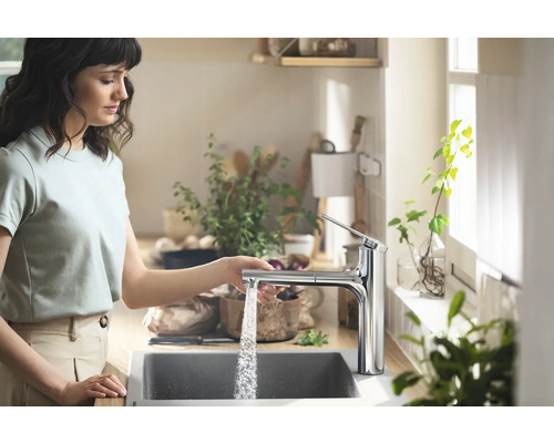 Femme utilisant un robinet de cuisine chromé dans une cuisine claire