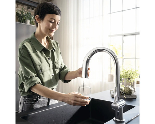 Frau befüllt Glas mit Wasserhahn an Spüle