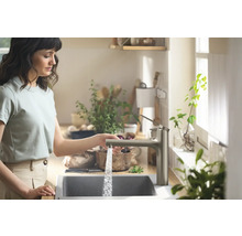 Frau mit Wasserhahn und Spüle in der Küche