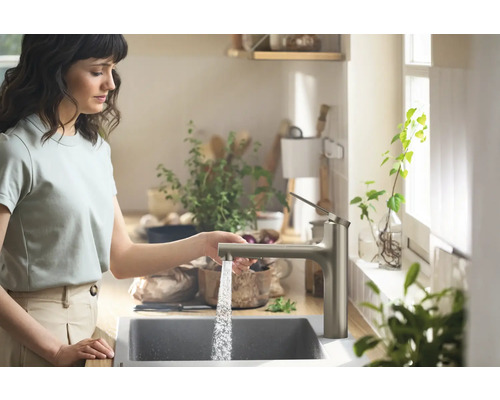 Frau mit Wasserhahn und Spüle in der Küche