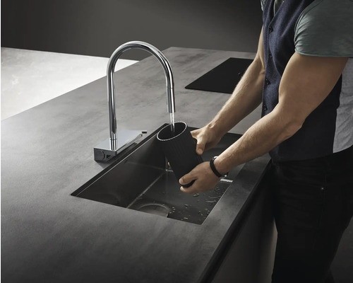 Mann wäscht einen Behälter in einem Spülbecken mit Wasserhahn.
