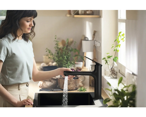 Frau bedient eine Küchenarmatur mit Wasserauslauf in einem modernen Küchendesign.