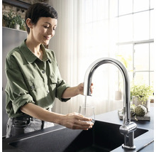 Femme remplissant un verre d''eau au robinet de cuisine chromé au-dessus de l''évier