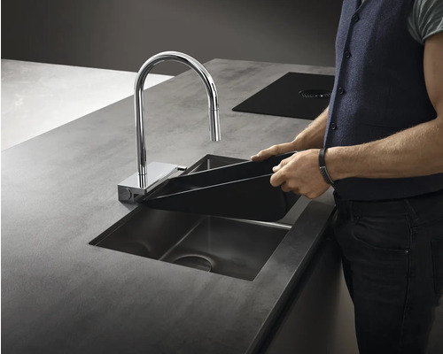 Küchenszene mit Spüle, Wasserhahn und einer Person, die ein schwarzes Becken hält