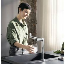 Femme remplissant un verre d''eau à l''évier avec robinet