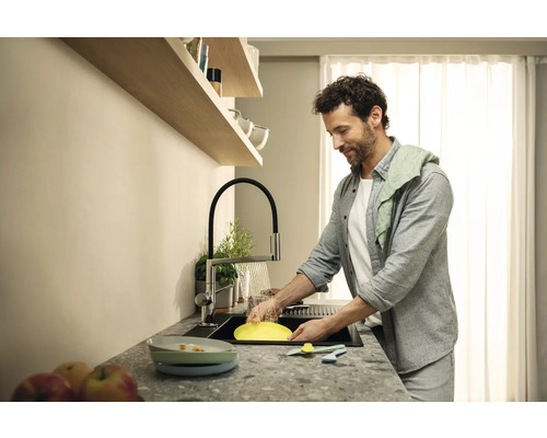 Un homme fait la vaisselle dans une cuisine moderne avec évier, robinet de cuisine et égouttoir