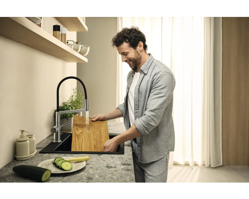 Mann spült Holzbrett in einer modernen Küche mit Spültischarmatur