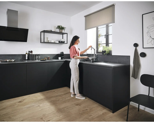 Moderne Küche mit schwarzen Schränken, Arbeitsplatte, Dunstabzugshaube und einer Frau am Waschbecken
