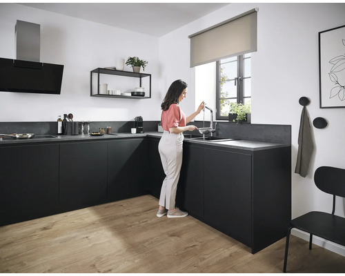 Cuisine moderne avec des armoires noires, un plan de travail et une femme à l''évier