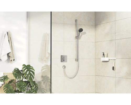 Espace douche avec ensemble de douche, robinetterie, étagère et serviettes dans une salle de bain lumineuse.