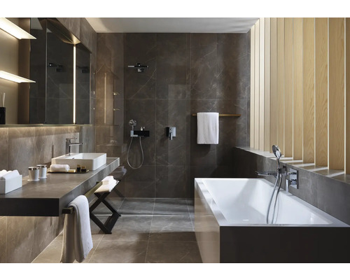 Modernes Badezimmer mit Badewanne, Waschtisch und grauen Fliesen.