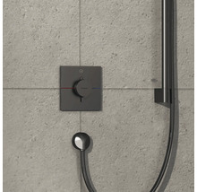 Brausethermostat mit Handbrause an einer grauen gefliesten Wand