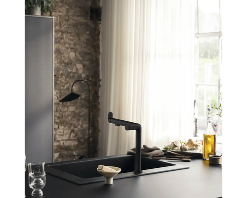 Scène de cuisine avec évier et robinet noirs devant une décoration de fenêtre.