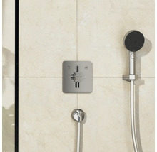 Thermostat de douche apparent avec douchette à main et flexible de douche sur un mur carrelé