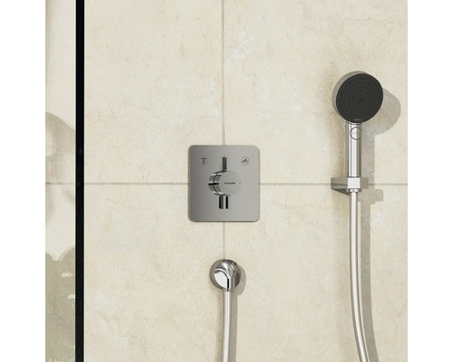 Thermostat de douche apparent avec douchette à main et flexible de douche sur un mur carrelé