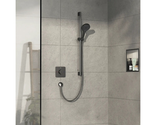 Duscharmatur mit Handbrause an einer Stange in einem Badezimmer mit hellgrauen Fliesen.