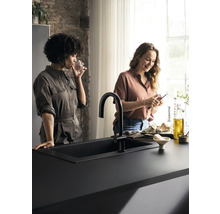 Évier noir avec robinet sur un comptoir de cuisine avec deux femmes.