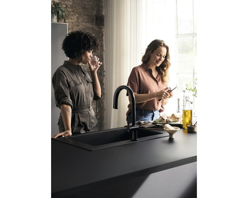 Zwei Frauen in einer Küche mit schwarzem Spülbecken und Armatur