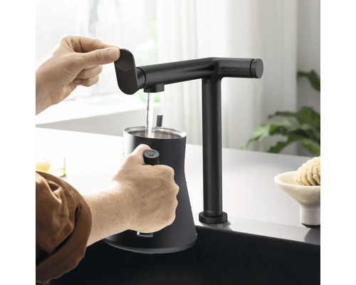 Une personne remplit un récipient avec un robinet de cuisine noir.