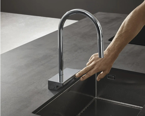 Küchenspüle mit Armatur und Finger auf einem Bedienfeld