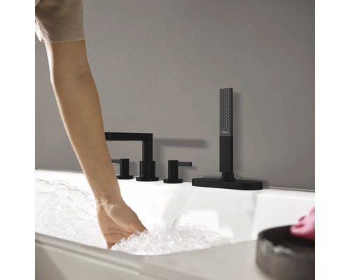Une femme fait couler de l''eau dans une baignoire avec une robinetterie noire.