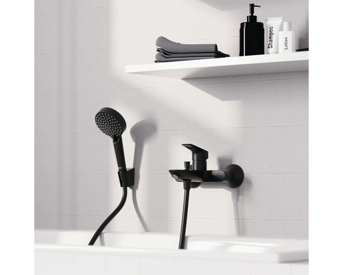 Schwarze Badewannenarmatur mit Handbrause und Ablage mit Shampoo, Lotion und Handtüchern