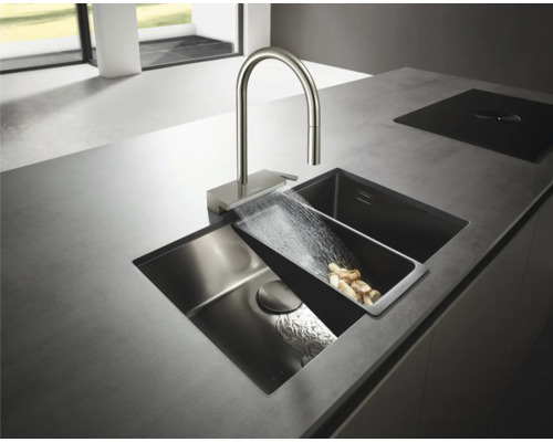 Küchenspüle mit Wasserhahn und Gemüse in einem Sieb