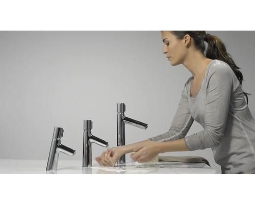 Frau wäscht Hände an Waschbecken mit drei Armaturen in unterschiedlicher Höhe.