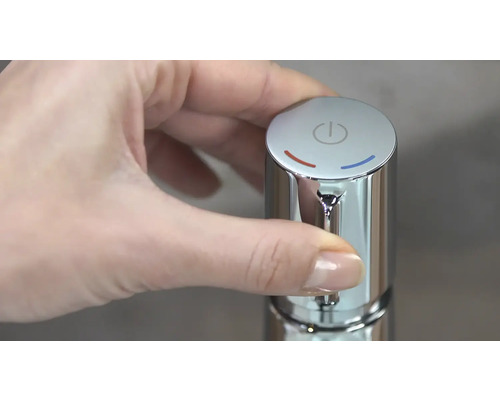 Une main actionne un robinet chromé avec contrôle de la température