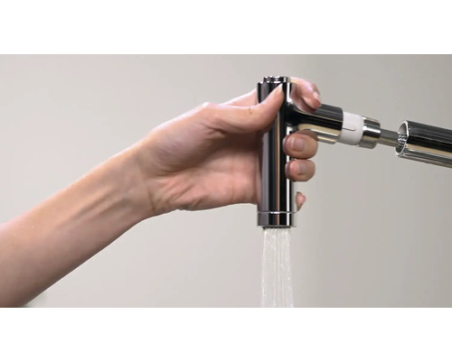 Hand hält eine glänzende Küchenarmatur, aus der Wasser fließt