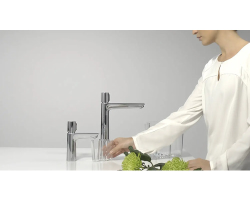 Zwei verchromte Armaturen mit Blumen und Gläsern dekoriert.