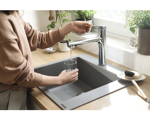 Femme remplissant un verre d''eau à un évier avec un robinet.