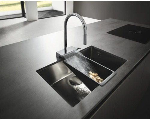Spüle mit Wasserhahn und Gemüseschale auf einer Küchentheke