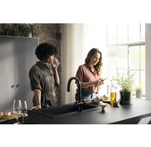 Cuisine claire avec évier, robinetterie et deux femmes préparant des plats